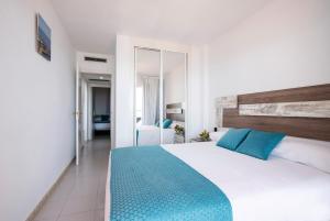 a bedroom with a large white bed with blue pillows at Pierre & Vacances Altea Beach - Port in Altea