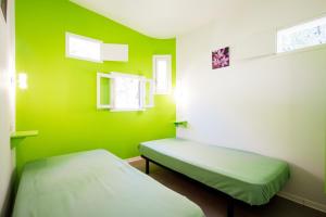 a green room with two beds and two windows at Les Bois De Prayssac in Prayssac