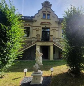 une grande maison avec une statue en face de celle-ci dans l'établissement Romantische Ferienwohnung im Herrenhaus Wüstenhain Spreewald, à Vetschau/Spreewald