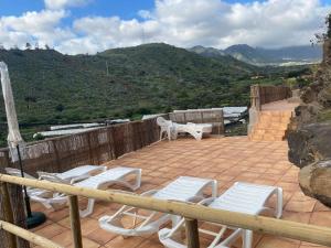 d'une terrasse avec des chaises blanches, des tables et des montagnes. dans l'établissement Villa Cueva Tecen Valsequillo, à Valsequillo de Gran Canaria