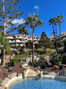een zwembad in een resort met palmbomen en een gebouw bij Albatros Golf & Sea View in San Miguel de Abona