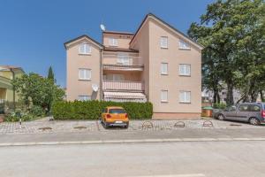 pomarańczowy samochód zaparkowany przed budynkiem w obiekcie Apartments Lovely Katarina w mieście Karigador