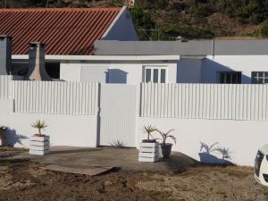 una cerca blanca con macetas delante de una casa en Casas de praia Sandra e Nelson, en Almada