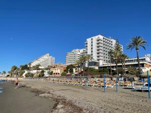 ベナルマデナにあるBenalmadena Playaのラウンジチェアと建物、街のビーチを提供しています。