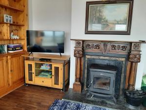 a living room with a fireplace and a television at Skye's Atlantic Retreat in Milltown Malbay
