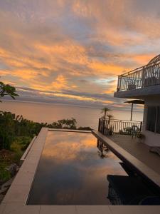a house with a swimming pool with a sunset at Oceano Con Vista Highland in Supa