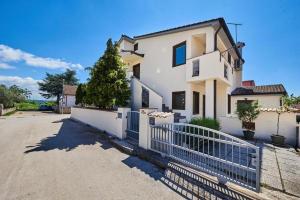 a white house with a fence in front of it at Apartment Iriska in Novigrad Istria