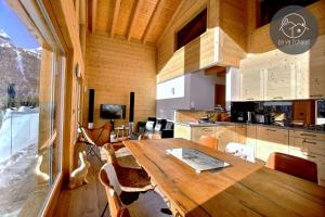 a kitchen and dining room with a wooden table and chairs at Chalet de charme l'O in Ovronnaz