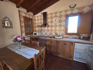 Casa Rural Amarilla في أفيلا: مطبخ مع طاولة عليها مزهرية من الزهور