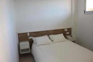 een slaapkamer met een wit bed en 2 witte kussens bij Relax en primera línea AP4 in El Campello