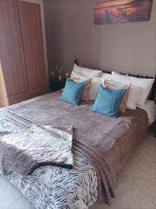 Una cama grande con almohadas azules encima. en Eirini's Apartment en Mesolóngion