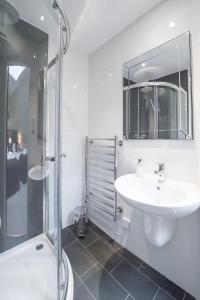 a white bathroom with a sink and a shower at Rossie Ochil House with Hot Tub in Forgandenny