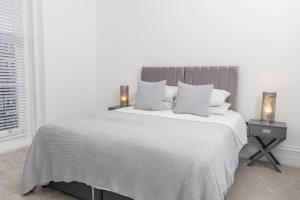 a white bedroom with a large bed with two lamps at Saint Margret in Cheltenham