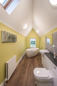 a bathroom with a tub and two sinks and a toilet at Rossie Ochil House with Hot Tub in Forgandenny
