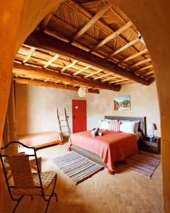 ein Schlafzimmer mit einem Bett und einem Stuhl in einem Zimmer in der Unterkunft Maison d'hôtes Tigminou - Adults Only in Aït-Ben-Haddou
