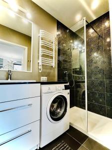 y baño con ducha y lavadora. en Baltic View Apartament - Dwie Sosny, en Ustronie Morskie