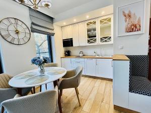 una cocina con mesa y sillas y un reloj en la pared en Baltic View Apartament - Dwie Sosny, en Ustronie Morskie