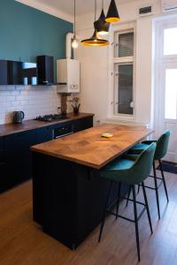 uma cozinha com uma mesa de madeira e cadeiras verdes em Central Szeged Apartment em Szeged