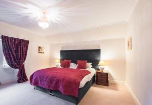 a bedroom with a large bed with a red blanket at Rossie Ochil House with Hot Tub in Forgandenny