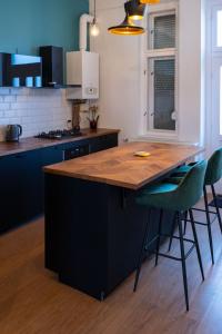 een keuken met een houten eiland met twee groene stoelen bij Central Szeged Apartment in Szeged