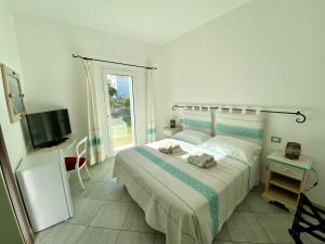 a white bedroom with a bed and a television at Tigrillo Bed&Breakfast in Olbia