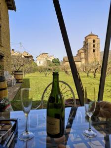 una botella de vino sentada en una mesa con dos copas en Casa Rural Barangua en el Pirineo Aragonés en Santa Cruz de la Serós