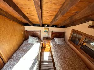 Dos camas en una habitación con techos de madera. en Casa Rural Naranja, en El Tiemblo