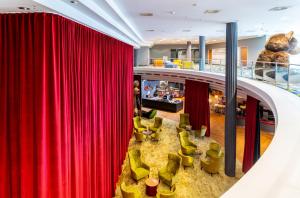 un escenario con cortinas rojas y sillas verdes en mightyTwice Hotel Dresden, en Dresden