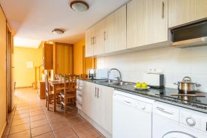a kitchen with white cabinets and a dining room with a table at Apartamentos Punta Prima By EscapeHome in Punta Prima