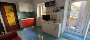 une petite cuisine avec une porte rouge et une télévision dans l'établissement casa arcobaleno, à Isola del Giglio
