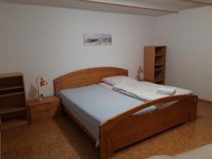 a bedroom with a large wooden bed with white sheets at Ferienwohnung im Seidlerhof mit Terrasse in Röhrnbach