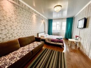 uma sala de estar com um sofá e uma cama em Apartments on Kuban 63 em Pavlodar