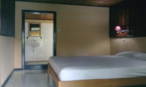 a bedroom with a bed and a door to a bathroom at Ue Datu Cottages in Tentena