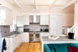 ウィスタブルにあるWhitstable Wishes, a Stylish Seaside Retreat, Whitstable with Parking Spaceのキッチン(白いキャビネット、コンロ付)