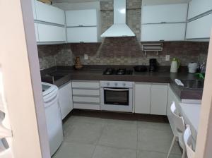 cocina con armarios blancos y fogones en Lindo Apartamento à Beira Mar, en João Pessoa