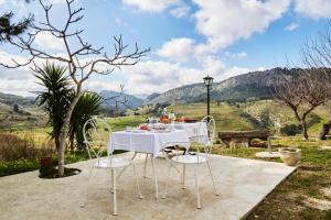 a table with white chairs and a view of mountains at Helimos Segesta in Brucanuova