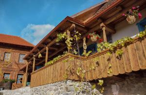 - un balcon en bois avec des plantes en pot sur une maison dans l'établissement Székelyföld ,Siklódi Kő Vendégház, Tornácosház, à Bartoştana