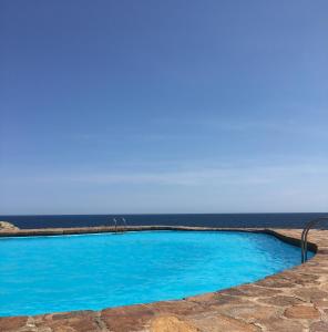 a blue swimming pool with the ocean in the background at Apartamento con playa y vistas en la Costa Brava in Begur