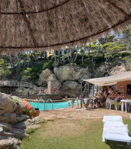una piscina en un complejo con gente sentada en mesas en Apartamento con playa y vistas en la Costa Brava en Begur