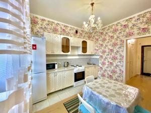 a kitchen with a table and a white refrigerator at 1 комнатные апартаменты in Pavlodar