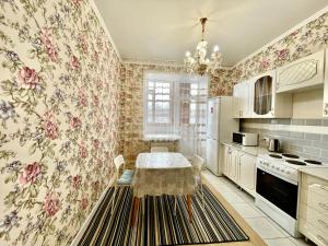 cocina con mesa y papel pintado con motivos florales en 1 комнатные апартаменты, en Pavlodar
