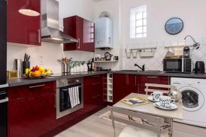 a kitchen with red cabinets and a table in it at Appartement biarritz beaurivage. Chez Rodolphe in Biarritz