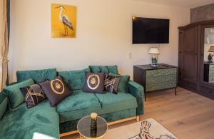 ein Wohnzimmer mit einem grünen Sofa und einem TV in der Unterkunft SweetHome - Luxus pur - Küche, Balkon, WiFi in Dachau