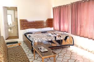 a bedroom with a bed and a table in a room at Hotel Sri Balaji in Ooty
