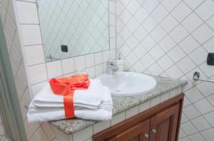 a bathroom with a sink and a towel with a ribbon at Casa Vacanza Le Fresie in Nuoro