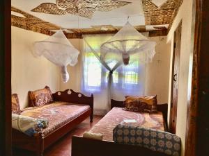 Zimmer mit 2 Betten, einem Sofa und einem Fenster in der Unterkunft Machame Homestay and Cultural Tourism in Machame