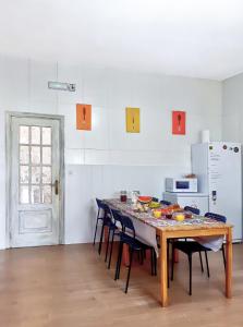 y cocina con mesa, sillas y nevera. en Meiga Backpackers Hostel, en Santiago de Compostela