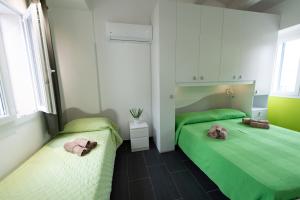 two beds in a room with green and white at Vacanze a Casa Pozzallo in Pozzallo