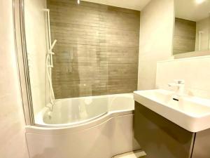 a bathroom with a white tub and a sink and a bath tub at Beautiful 2 Bedroom Apartment - 1 Minute walk to Poole Quay - Great Location - Free Parking - Fast WiFi - Smart TV - Newly decorated - sleeps up to 4! Close to Poole & Bournemouth & Sandbanks in Poole