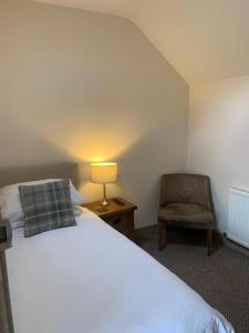 a bedroom with a bed and a chair and a lamp at Palmer's Ale House in Long Sutton